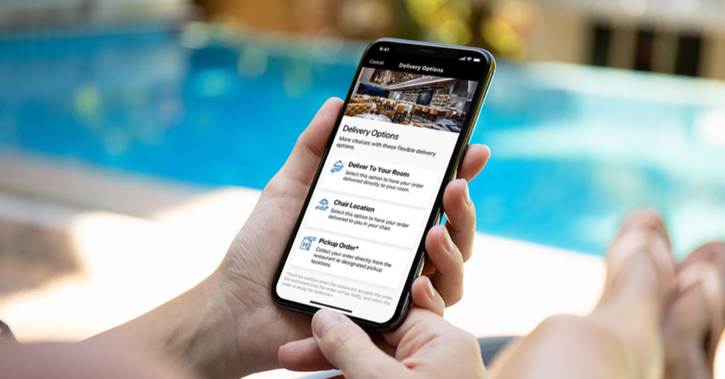 Photo of a person holding a phone while next a pool. The phone screen shows in-app delivery options